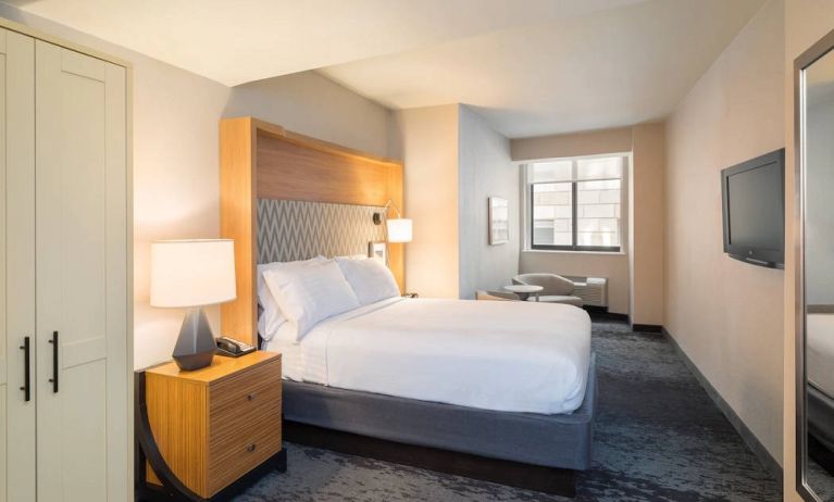 Guest room in the Holiday Inn Express Wall Street, with large television, chairs, and window.