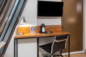 An in-room workspace at La Quinta Times Square South, with desk, chair, lamp, and TV.