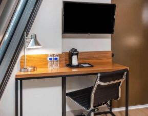 An in-room workspace at La Quinta Times Square South, with desk, chair, lamp, and TV.
