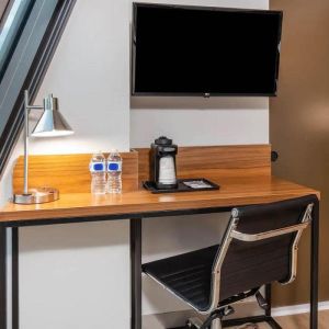 An in-room workspace at La Quinta Times Square South, with desk, chair, lamp, and TV.