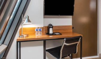 An in-room workspace at La Quinta Times Square South, with desk, chair, lamp, and TV.