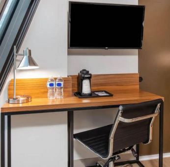 An in-room workspace at La Quinta Times Square South, with desk, chair, lamp, and TV.