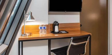 An in-room workspace at La Quinta Times Square South, with desk, chair, lamp, and TV.