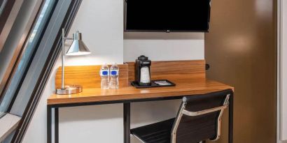 An in-room workspace at La Quinta Times Square South, with desk, chair, lamp, and TV.