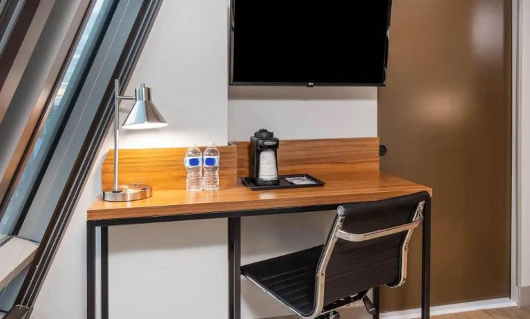 An in-room workspace at La Quinta Times Square South, with desk, chair, lamp, and TV.