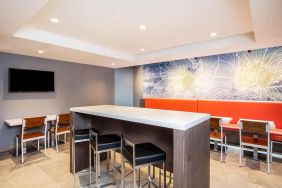 The hotel’s breakfast area, with hard floor, regular chairs and tables, and tall stools.