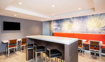 The hotel’s breakfast area, with hard floor, regular chairs and tables, and tall stools.