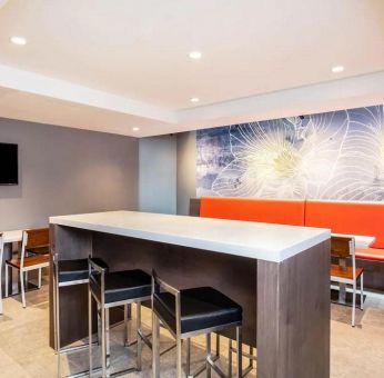 The hotel’s breakfast area, with hard floor, regular chairs and tables, and tall stools.