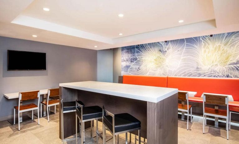 The hotel’s breakfast area, with hard floor, regular chairs and tables, and tall stools.