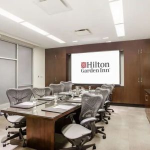 A hotel meeting room, with eight chairs arranged around a long table.