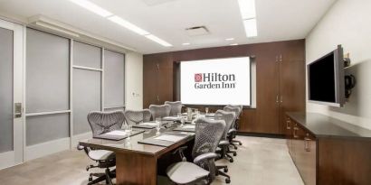 A hotel meeting room, with eight chairs arranged around a long table.