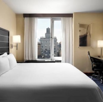 Delux king room with TV and business desk at Hilton New York Fashion District.