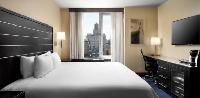 Delux king room with TV and business desk at Hilton New York Fashion District.