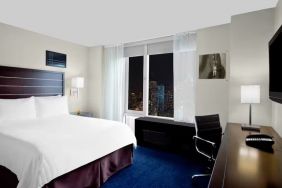 King bedroom with TV and work station at Hilton New York Fashion District.