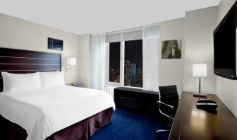 King bedroom with TV and work station at Hilton New York Fashion District.