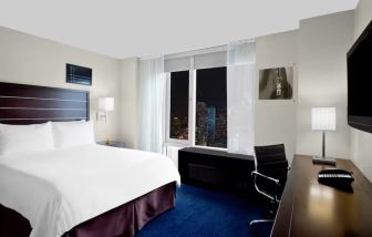 King bedroom with TV and work station at Hilton New York Fashion District.