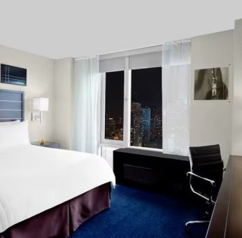 King bedroom with TV and work station at Hilton New York Fashion District.