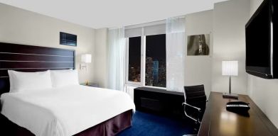 King bedroom with TV and work station at Hilton New York Fashion District.