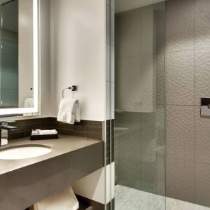 Private guest bathroom with shower at The Rose Hotel Chicago O’Hare, Tapestry Collection By Hilton.