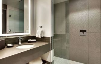 Private guest bathroom with shower at The Rose Hotel Chicago O’Hare, Tapestry Collection By Hilton.