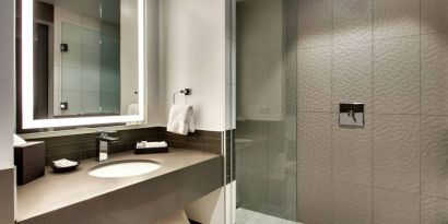 Private guest bathroom with shower at The Rose Hotel Chicago O’Hare, Tapestry Collection By Hilton.