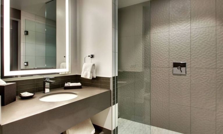 Private guest bathroom with shower at The Rose Hotel Chicago O’Hare, Tapestry Collection By Hilton.