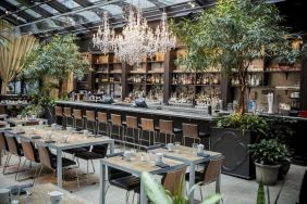 The hotel’s restaurant and bar, with table seating, tall barstools, and plenty of plant life.