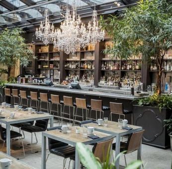 The hotel’s restaurant and bar, with table seating, tall barstools, and plenty of plant life.