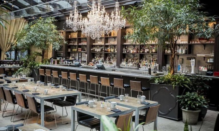 The hotel’s restaurant and bar, with table seating, tall barstools, and plenty of plant life.