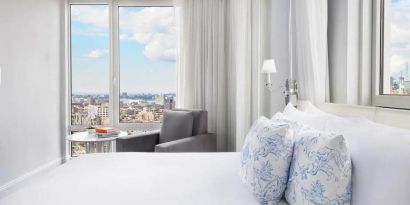 One of the NoMo Soho’s guest rooms, with double bed, chair, and great view of the city.