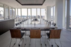 One of the hotel meeting rooms, with over a dozen seats arranged around long tables, and panoramic city views.