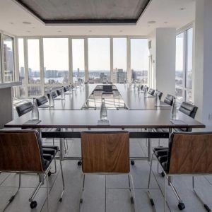 One of the hotel meeting rooms, with over a dozen seats arranged around long tables, and panoramic city views.