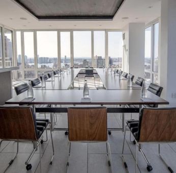 One of the hotel meeting rooms, with over a dozen seats arranged around long tables, and panoramic city views.