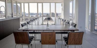 One of the hotel meeting rooms, with over a dozen seats arranged around long tables, and panoramic city views.