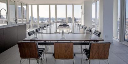 One of the hotel meeting rooms, with over a dozen seats arranged around long tables, and panoramic city views.