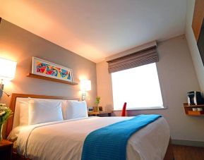 One of Edge Hotel NYC’s guest rooms, featuring double bed, window, and bedside table.