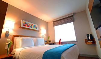 One of Edge Hotel NYC’s guest rooms, featuring double bed, window, and bedside table.