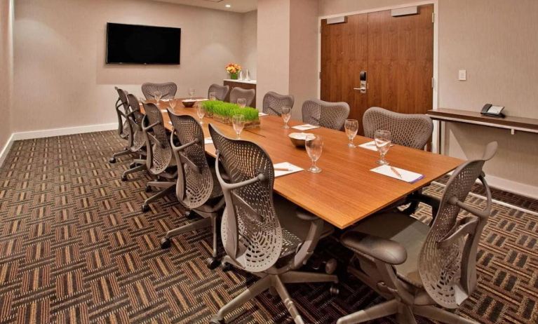 Meeting room with long wooden table and a dozen swivel chairs around it.