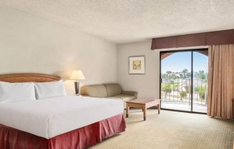 Comfortable king bed with natural light and terrace at Golden Sails Hotel Long Beach.