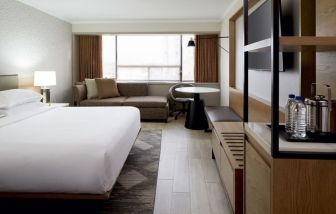 King bed with TV and lounge area at Sheraton Montreal Airport Hotel.