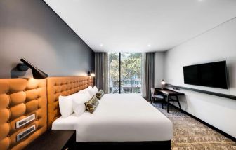 Comfortable king bed with TV and business desk at Vibe Hotel North Sydney.