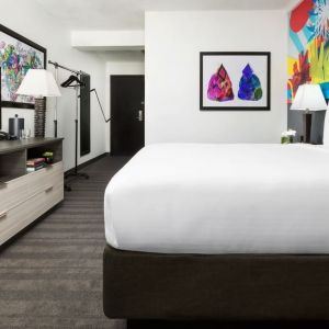 Spacious king bedroom with TV and natural light at Hotel Studio Allston.