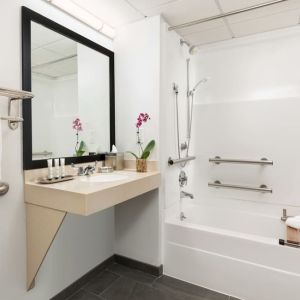 Private guest bathroom with bath and shower at Hotel Studio Allston.