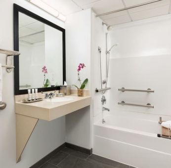 Private guest bathroom with bath and shower at Hotel Studio Allston.