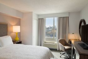 King bedroom with TV, desk, and natural light at Hampton Inn Manhattan Chelsea.