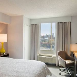 King bedroom with TV, desk, and natural light at Hampton Inn Manhattan Chelsea.