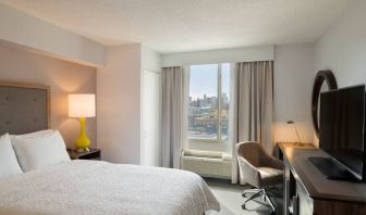 King bedroom with TV, desk, and natural light at Hampton Inn Manhattan Chelsea.