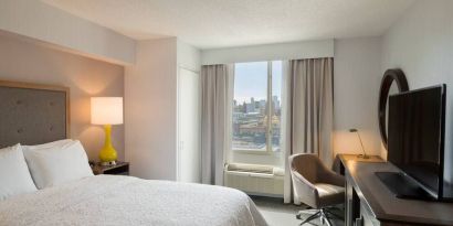 King bedroom with TV, desk, and natural light at Hampton Inn Manhattan Chelsea.