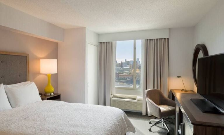 King bedroom with TV, desk, and natural light at Hampton Inn Manhattan Chelsea.