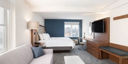 King bed with TV and business desk at Holiday Inn Express & Suites Boston-Cambridge.